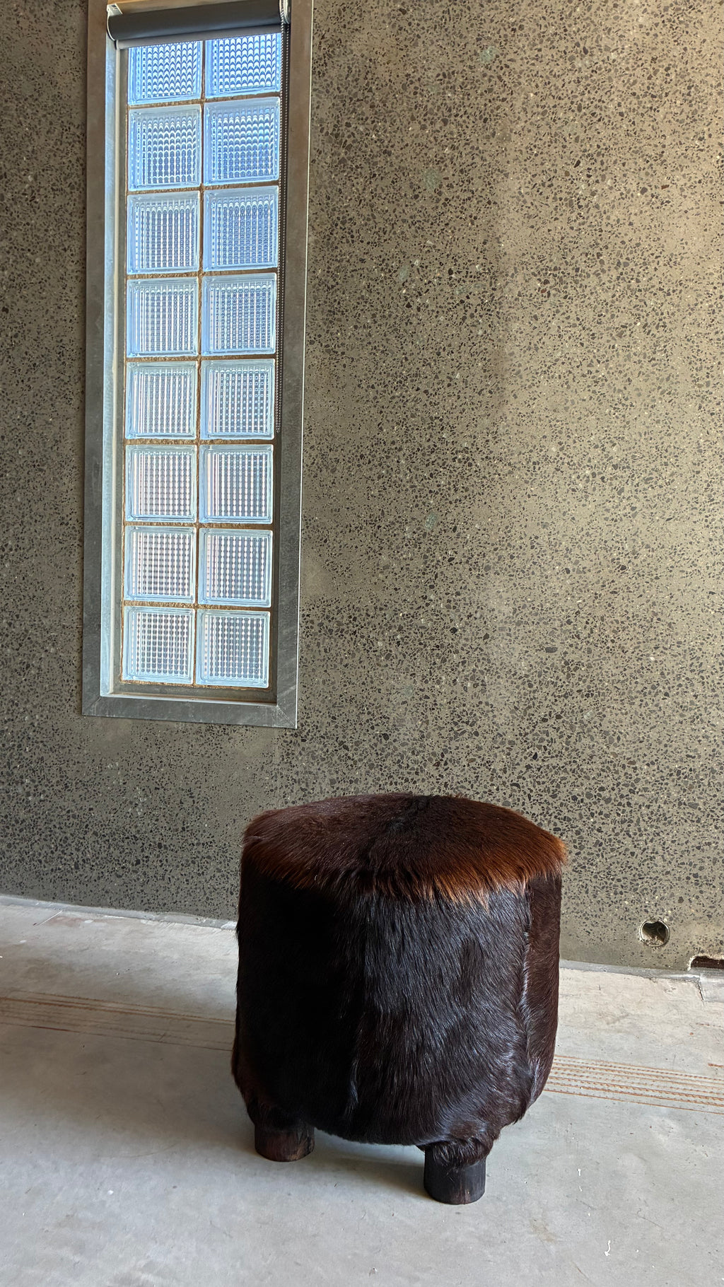 Mid-century cow hide footstool with carved timber feet 1970s