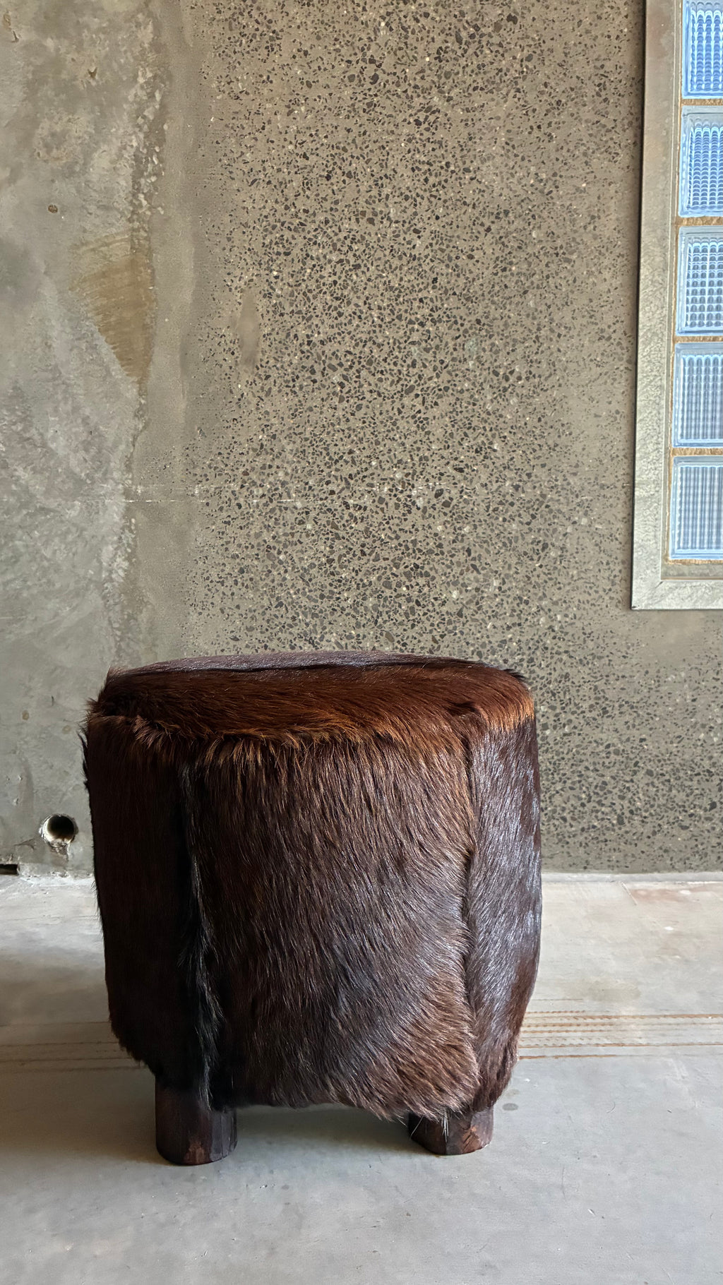 Mid-century cow hide footstool with carved timber feet 1970s